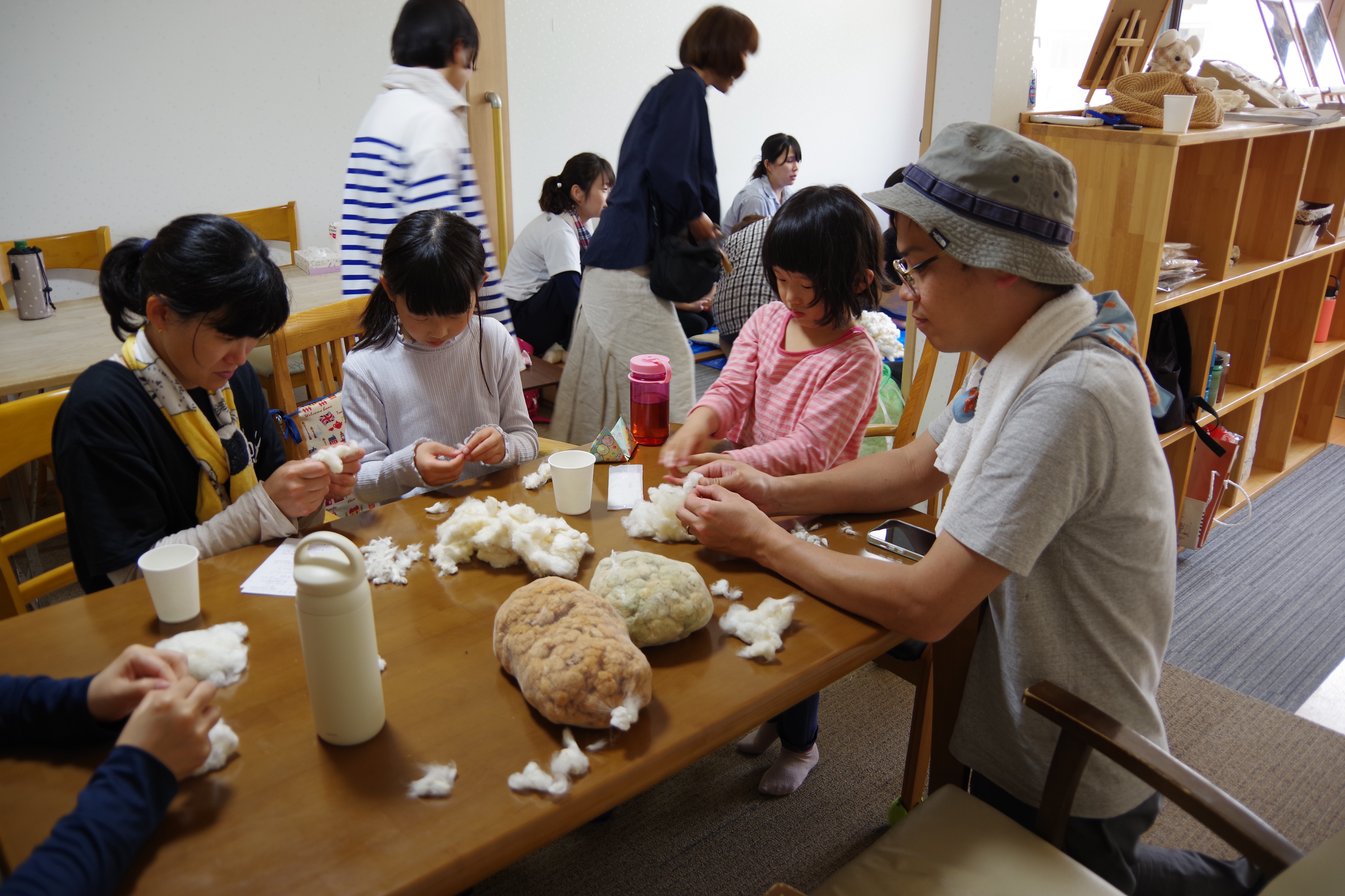 綿繰り（綿から種をはずす）作業をしている参加者たち。