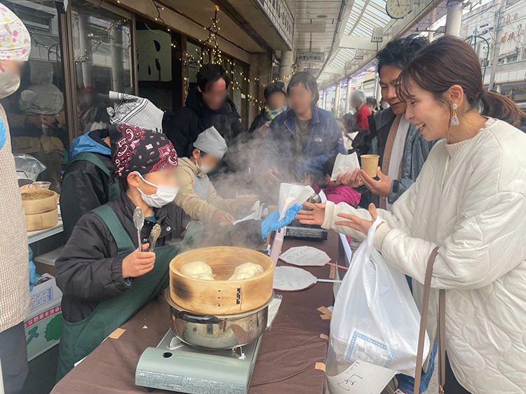 商店街のイベントで豚まんを買う瀬川さんご夫妻